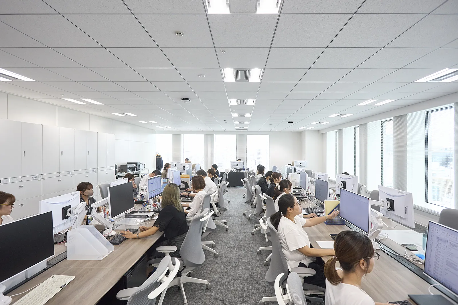 明るく開放的なオフィスで社員がデスクワークを行う執務スペース